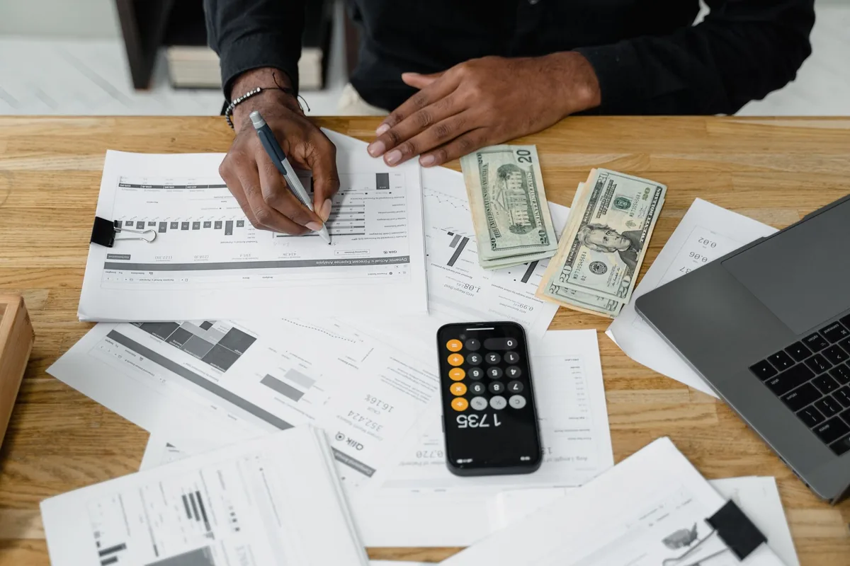 Contador revisando estados financieros con gráficas, calculadora y laptop